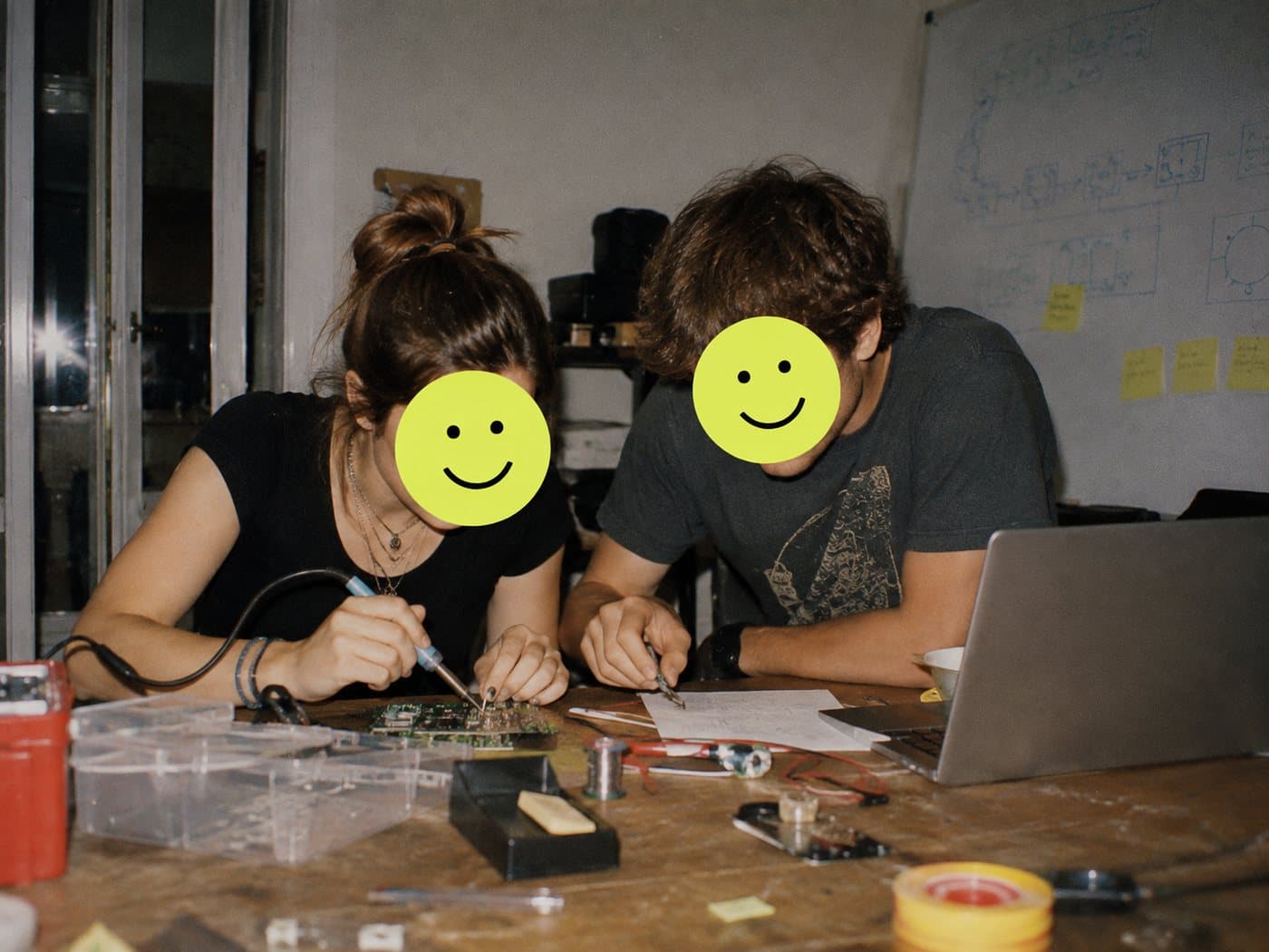 Two founders soldering their first prototype late at night